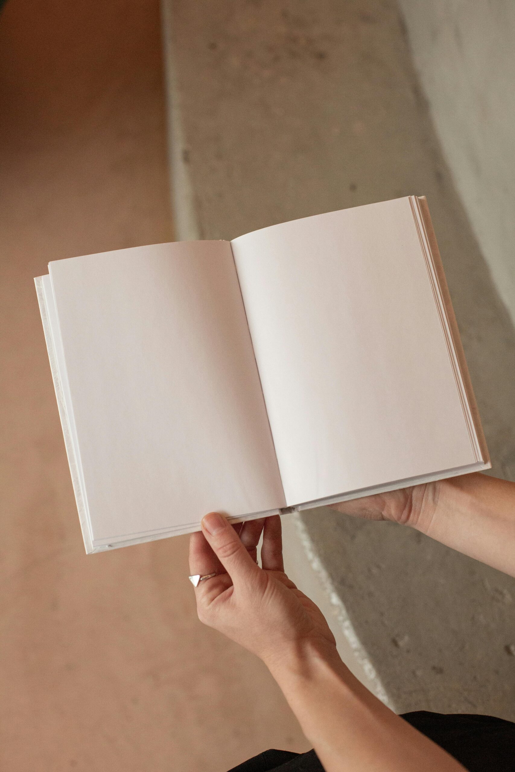 Mains qui tiennent un cahier de note vide. Cette personne s'apprête à écrire son prochain article. 